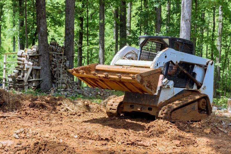 travaux de terrassement le tracteur nivele le sol de la forêt avec un godet